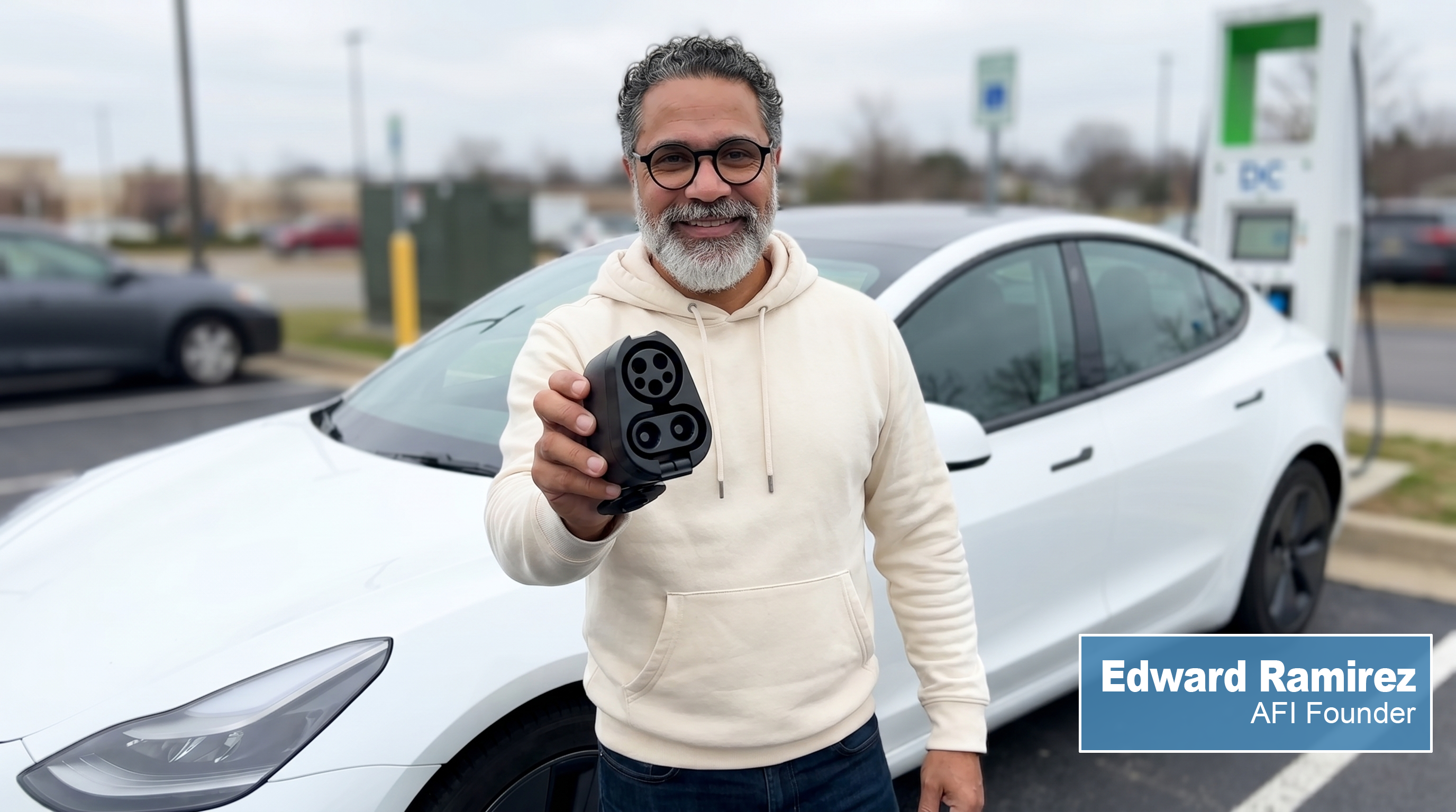 Edward Ramirez, AFI Founder, holding an AFI adapter in front of a Tesla